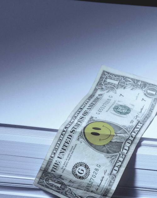 A single dollar note hangs off a pile of plain white paper