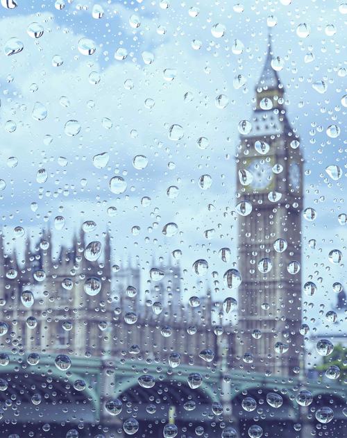 Blue tinted image of Big Ben and Westminster as seen through a window with rain drops on it