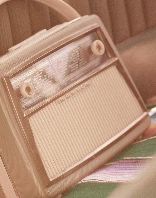 A vintage radio sits on the back seat of a vintage car